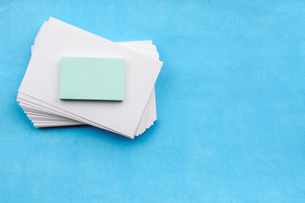 Un diseño de papelería sobre un fondo azul, una pila de pegatinas de tarjetas blancas en blanco y un despertador