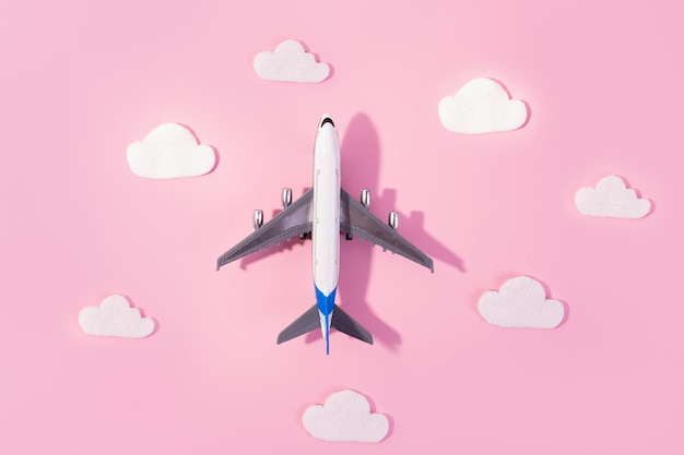 Diseño plano del concepto de viaje con avión y nube sobre fondo rosa y rosa con espacio de copia