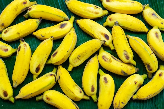 Diseño plano de plátanos amarillos sobre una hoja de plátano verde. Comida ecológica