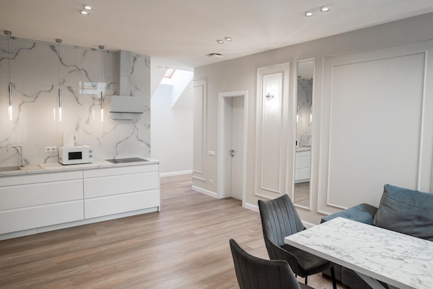 Diseño de la sala de la cocina en un color claro con mesa y electrodomésticos.