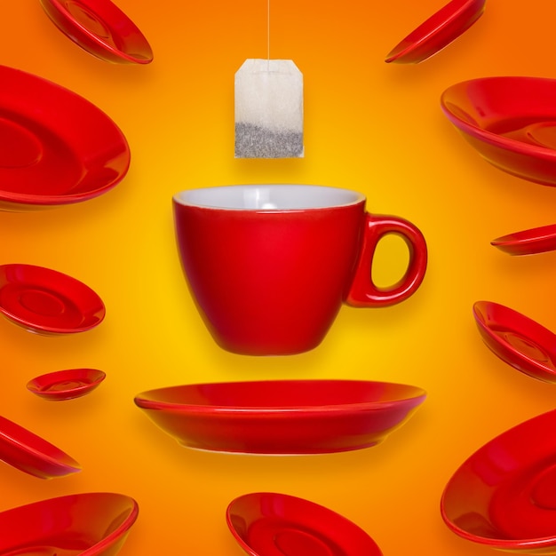 Diseño surrealista creativo con una taza y platillo de café rojo y una bolsita de té