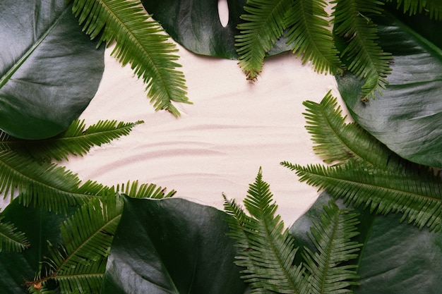 Diseño tropical de hojas de palma con espacio de copia sobre fondo de arena. Endecha plana.