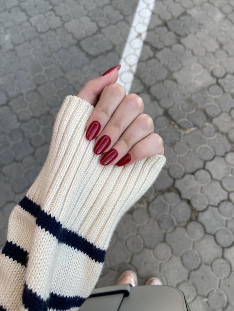 Diseño de uñas estéticas de mujer rojo sobre un fondo gris.