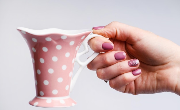 Diseño de uñas Manos con manicura de primavera rosa brillante sobre fondo gris