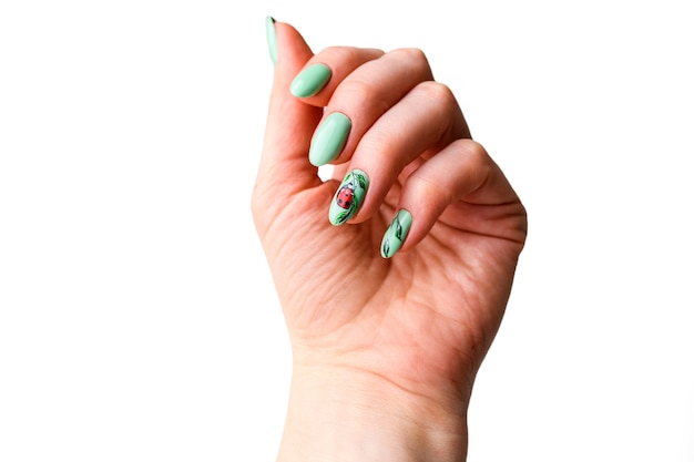 Diseño de Uñas. Manos con manicura verde brillante con flores. Cerca de las manos femeninas. Arte de uñas.