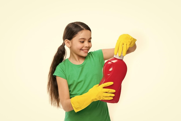 Foto disfruta lavando su ropa linda limpiadora usando guantes de goma amarillos niño pequeño sosteniendo detergente para ropa en las manos usando un producto de limpieza para el hogar niño pequeño listo para el lavado doméstico