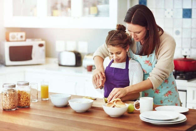 Disfrutamos de días como estos Toma de una madre y su hija preparando la comida en la cocina de casa