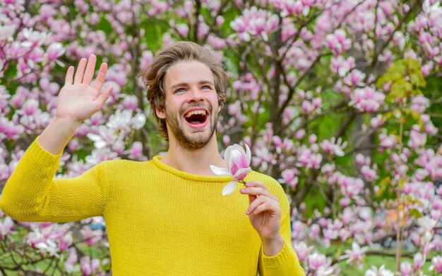 Disfrutando cada momento. fondo de sakura. disfruta del buen tiempo. árbol de magnolia de hombre sin afeitar. chico sexy árbol floreciente de la flor. flor de flor fresca. estilo de moda de primavera. Sexualidad masculina.