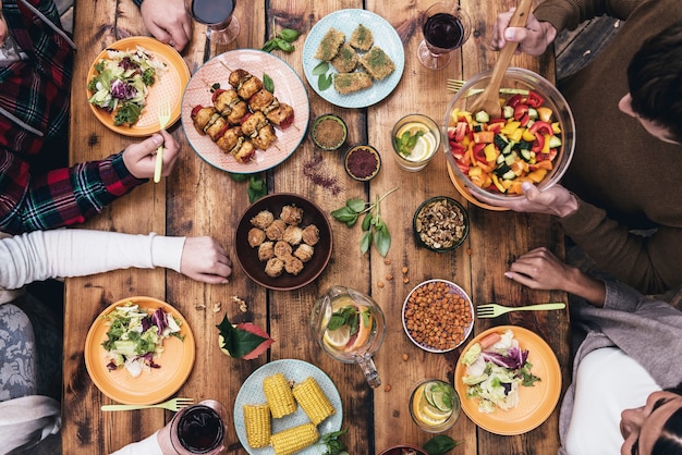 Disfrutando de la cena juntos. Vista superior de cuatro personas cenando juntas