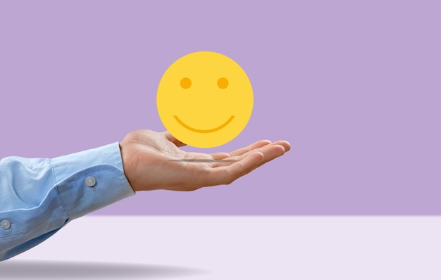 Disfrutando del concepto de la mano sosteniendo un icono de cara sonriente Signo de estilos de vida felices