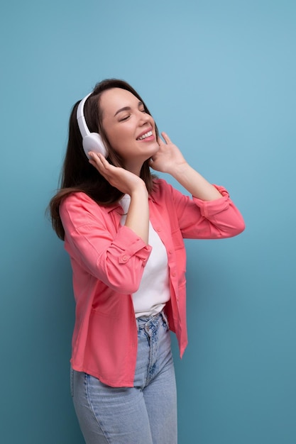 Disfrutando de una joven morena con cabello oscuro debajo de sus hombros en una camisa y jeans con conexión inalámbrica