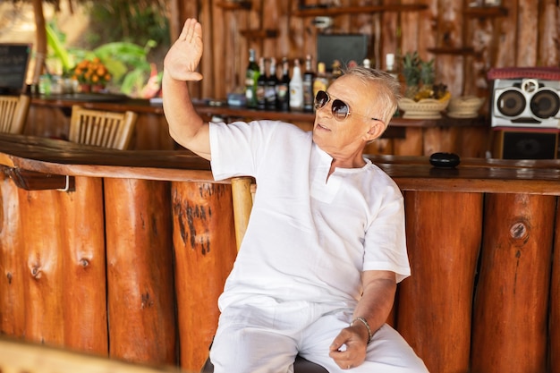 Disfrutando de la jubilación. Hombre mayor feliz sentado en el bar de la playa