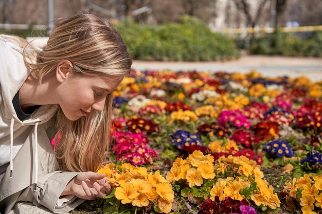 Disfrutando de las primeras flores de la primavera, una joven caucásica toca suavemente una flor