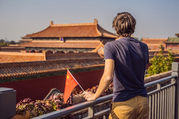 Disfrutando de vacaciones en China Joven con bandera nacional china en la Ciudad Prohibida Concepto de viaje a China Tránsito sin visa 72 horas 144 horas en China