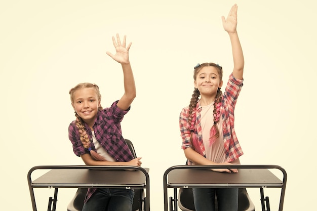 Disfrutar del proceso de estudio Niñas amigas de la escuela estudian juntas Levantar las manos para responder Los estudiantes compañeros de clase se sientan en el escritorio Regreso a la escuela Concepto de escuela privada Educación primaria