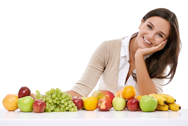 Disfrute de la generosidad de la naturaleza Una joven sonriente sentada junto a una selección de frutas