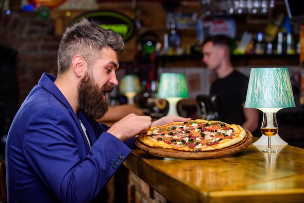 Disfrute de su comida Concepto de comida trampa Hipster hambriento comer pizza italiana Pizza comida favorita del restaurante Pizza caliente fresca para la cena Cliente hipster sentarse en la barra del bar El hombre recibió una pizza deliciosa