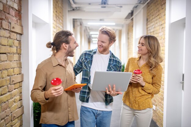 Diskutieren. Junge Mitarbeiter beobachten etwas auf einem Tablet und diskutieren es