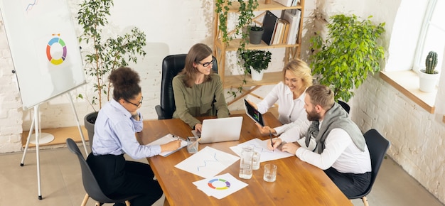 Diskutieren. Kollegen arbeiten in einem modernen Büro mit Geräten und Gadgets während kreativer Besprechungen zusammen.