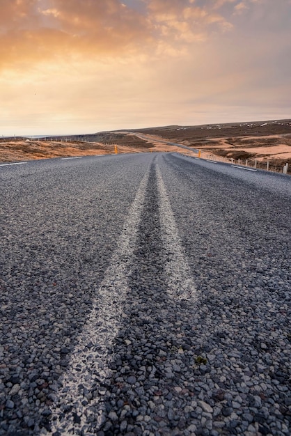 Disminución de la carretera vacía en medio del paisaje en el valle volcánico contra el cielo durante la puesta de sol