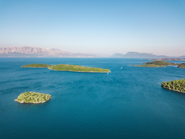 Dispara desde un dron en el mar azul con pequeñas islas y la costa mediterránea en el fondo. Vista de ángulo alto sobre la bahía de Nydri y las pequeñas islas circundantes en la costa este de la isla de