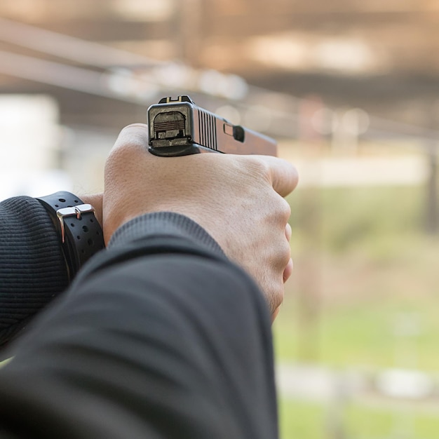 Disparando con una pistola. Hombre apuntando con pistola en el campo de tiro.