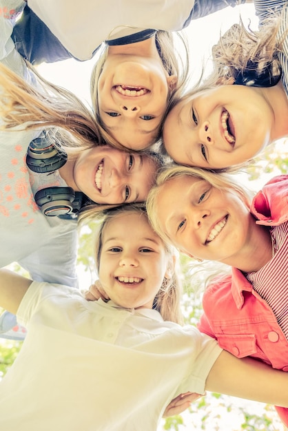 Disparo desde abajo de felices niñas sonrientes de pie en círculo