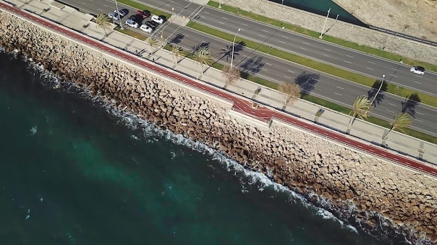 Disparo aéreo después de los coches en la autopista a lo largo de una costa rocosa vista aérea de