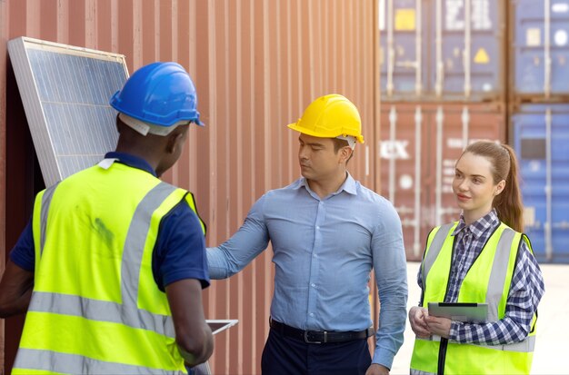 Disparo al aire libre del ingeniero africano negro inspeccionar el panel solar eléctrico con casco, gafas protectoras y equipo de seguridad,