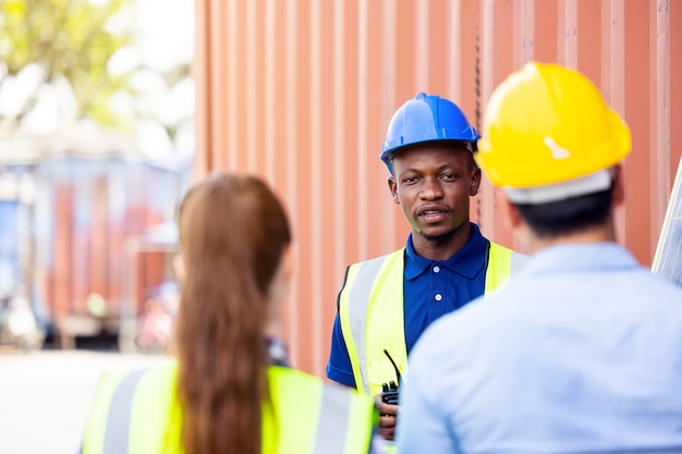 Disparo al aire libre del ingeniero africano negro inspeccionar el panel solar eléctrico con casco, gafas protectoras y equipo de seguridad,