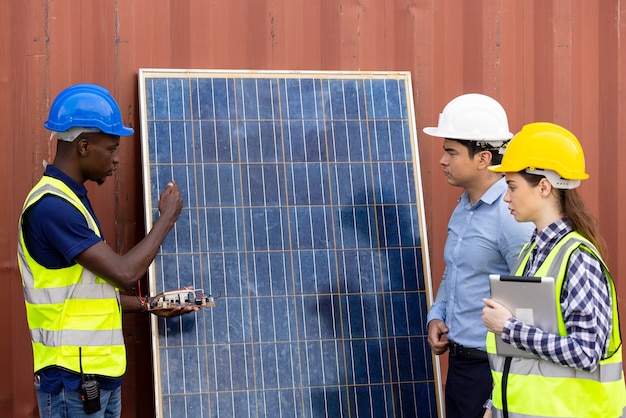 Disparo al aire libre del ingeniero africano negro inspeccionar el panel solar eléctrico con casco, gafas protectoras y equipo de seguridad,