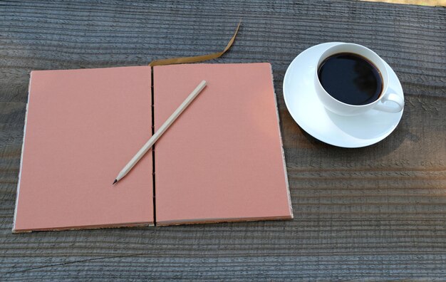 disparo de alto ángulo de crema marrón en blanco diario libro de notas de papel y un lápiz en el escritorio de madera pausa para el café