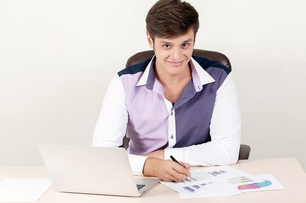 Disparo de un apuesto empresario director creativo hombre de negocios trabajando en la oficina mientras está sentado en el escritorio con ordenador portátil.
