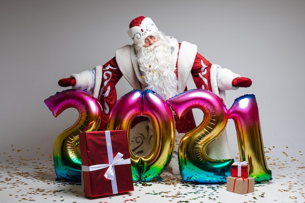 Disparo en la cabeza de Santa Claus con sombrero rojo, hombre cansado de pelo gris sobre fondo gris de estudio. Foto de alta calidad