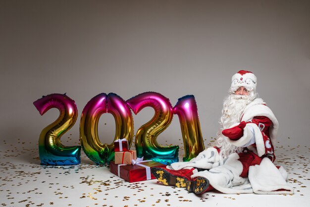 Disparo en la cabeza de Santa Claus con sombrero rojo, hombre cansado de pelo gris sobre fondo gris de estudio. Foto de alta calidad