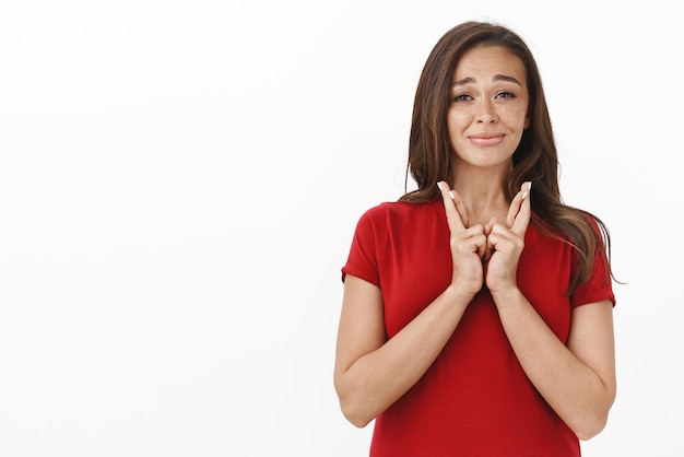 Foto disparo en la cintura nerviosa linda jovencita esperanzada preocupada por el casting importante cruzar los dedos buena suerte suplicando fortuna hacer realidad el sueño haciendo expresión ansiosa pensativa sonriendo intensamente