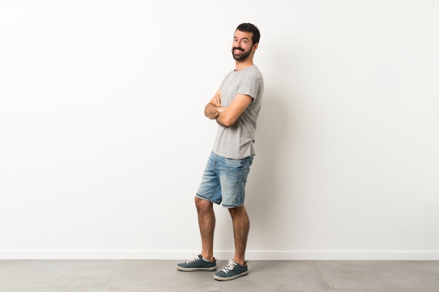 Un disparo de cuerpo entero de hombre guapo con barba con los brazos cruzados y mirando hacia adelante