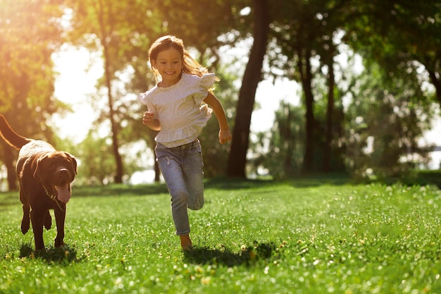 Disparo de cuerpo entero de niña corriendo en el parque con su perro