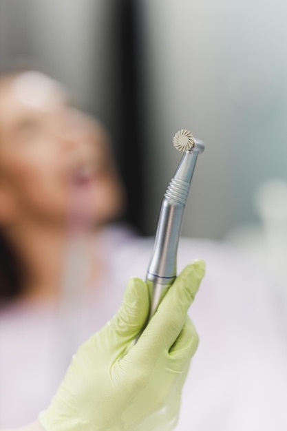 Disparo de un dentista irreconocible que sostiene herramientas dentales en una oficina.