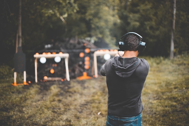 Disparo de enfoque superficial de un hombre disparando un arma en el campo de tiro