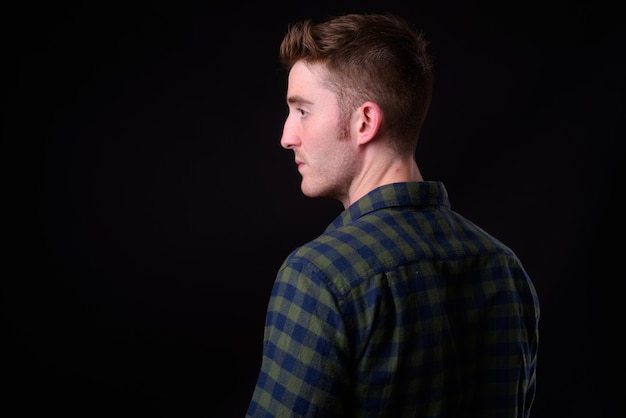 Foto disparo de estudio de joven guapo hipster contra fondo negro