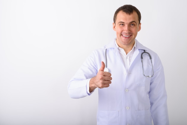 Disparo de estudio de joven médico hombre musculoso feliz sonriendo mientras giv