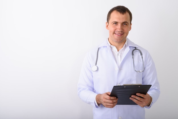 Disparo de estudio de joven médico hombre musculoso feliz sonriendo mientras hol