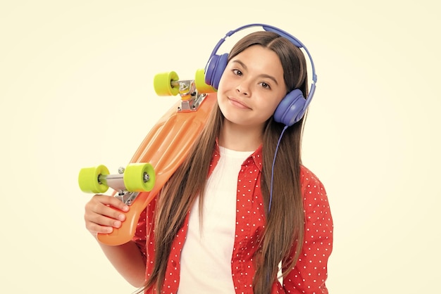 Foto disparo de estudio de modelo de moda adolescente de moda en look casual adolescente joven hipster estilo de vida urbano niña en estilo callejero en ropa hipster con una botella de agua de patineta y auriculares