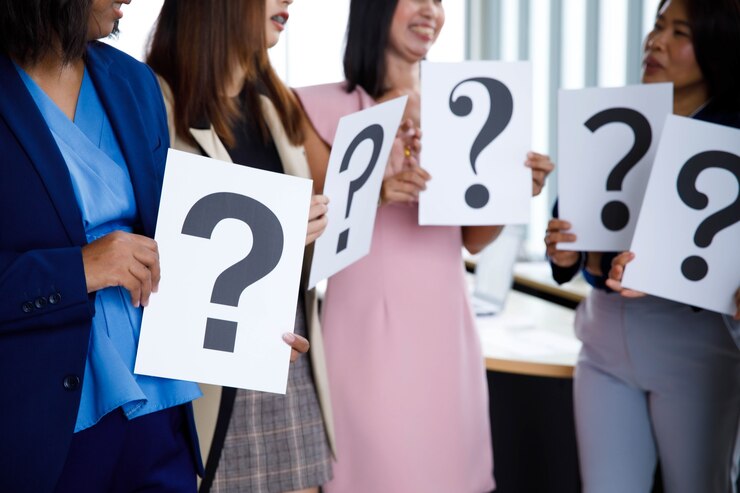 Foto disparo de estudio de oficial de personal femenino sin rostro no identificado irreconocible en traje de negocios que lleva una variedad de fuentes de papel de signo de interrogación en manos dudosas para obtener respuestas sobre fondo blanco.