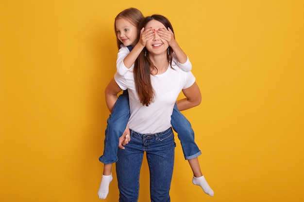 Disparo en el interior de la feliz madre que lleva a cuestas a la hija mientras un niño lindo cierra los ojos