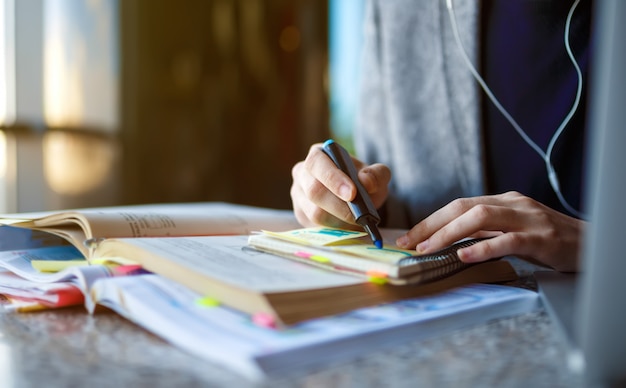 Disparo de joven estudiante masculino sentado en la mesa y escribir en el cuaderno. Joven estudiante masculino estudiando en la cafetería.