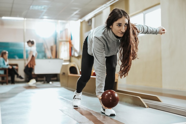 Disparo de una linda mujer joven lanzando la bola de bolos.