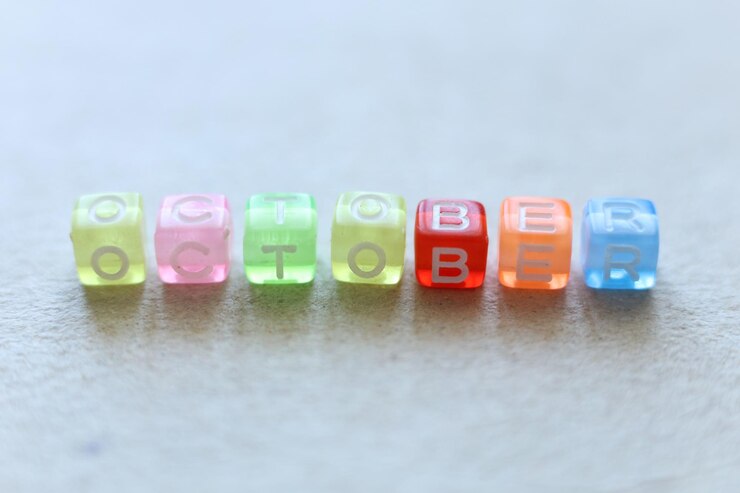 Foto disparo macro de cuentas coloridas que deletrean la palabra octubre en un fondo claro