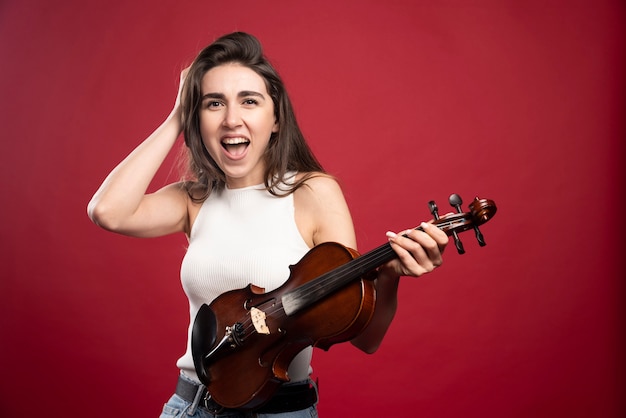 Disparo de modelo de mujer joven sosteniendo el violín para la lección de música